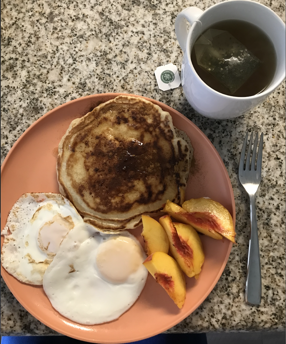 Pancake, eggs, and fruit with a cup of tea
