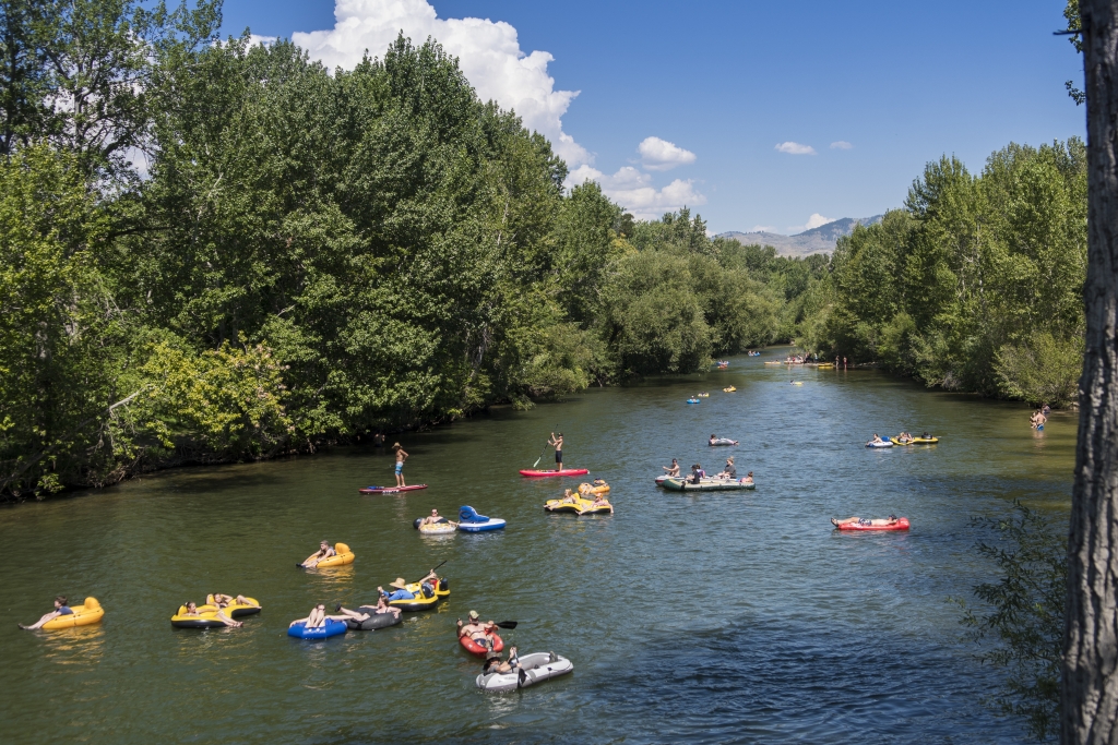 Students in kayaks and floaties ride the Boise River.
