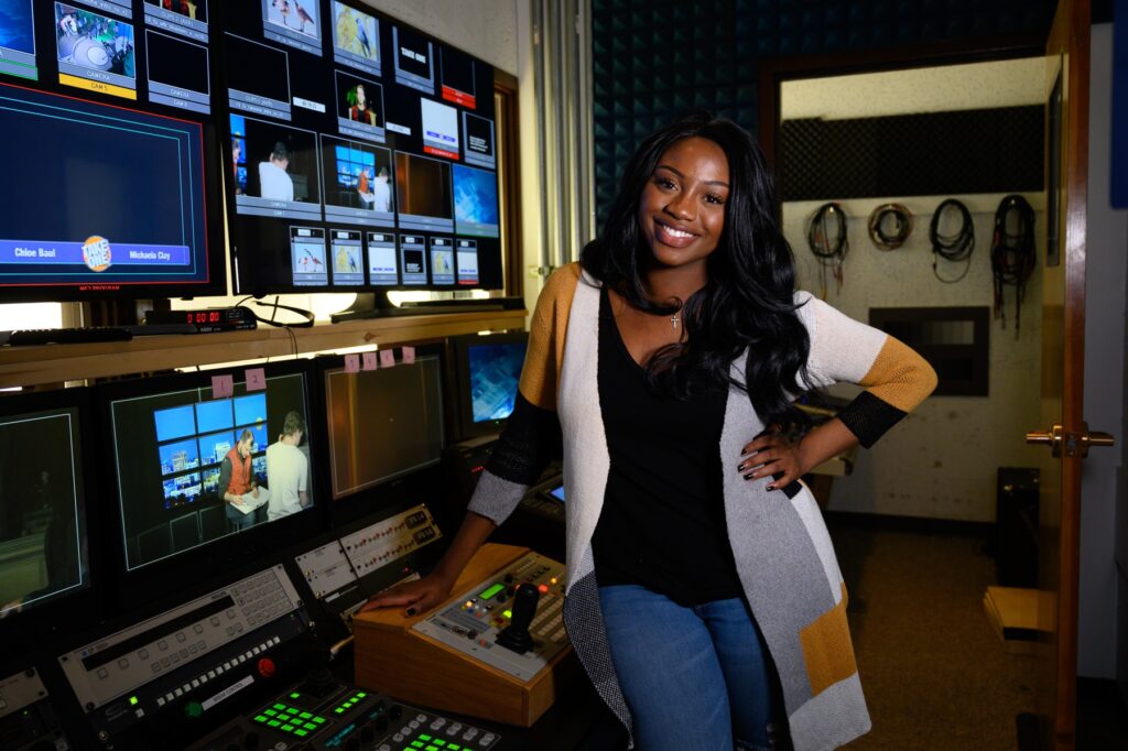 A student standing in a studio control room.