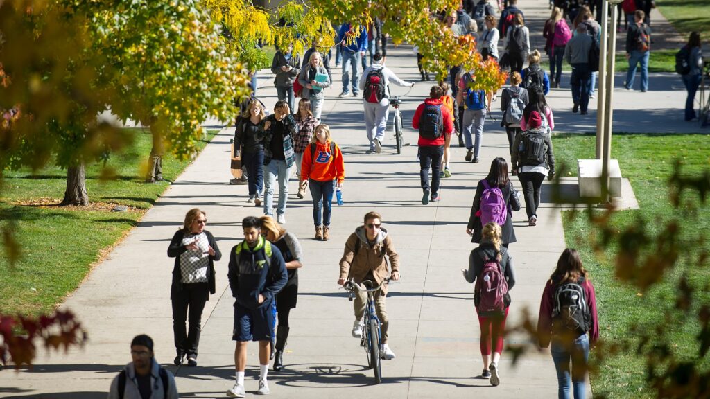 Students walking and biking to class along a busy pathway.