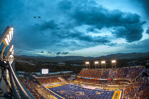 Bronco stadium at dusk with band on the field and two jets making a pass overhead