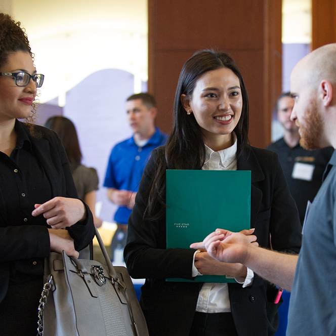 Enterprise employee talking with students at a networking event