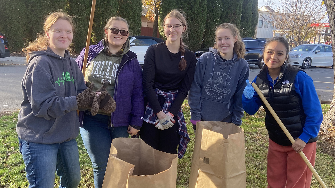 four female students bagging leaves for community members