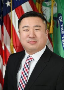 headshot of man in black suit and checkered red white and blue tie. Andy Tsui
