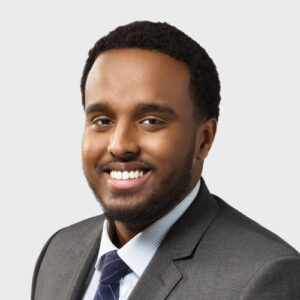 smiling man in grey suit with dark blue tie. Prof. Abdi Aidid