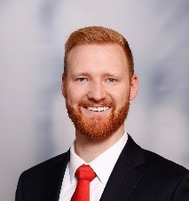 headshot of man in black suit wearing red tie. Jeff Olson