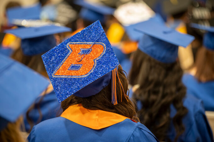 Students sitting at a graduation ceremony. Student's cap has a B decoration added to it