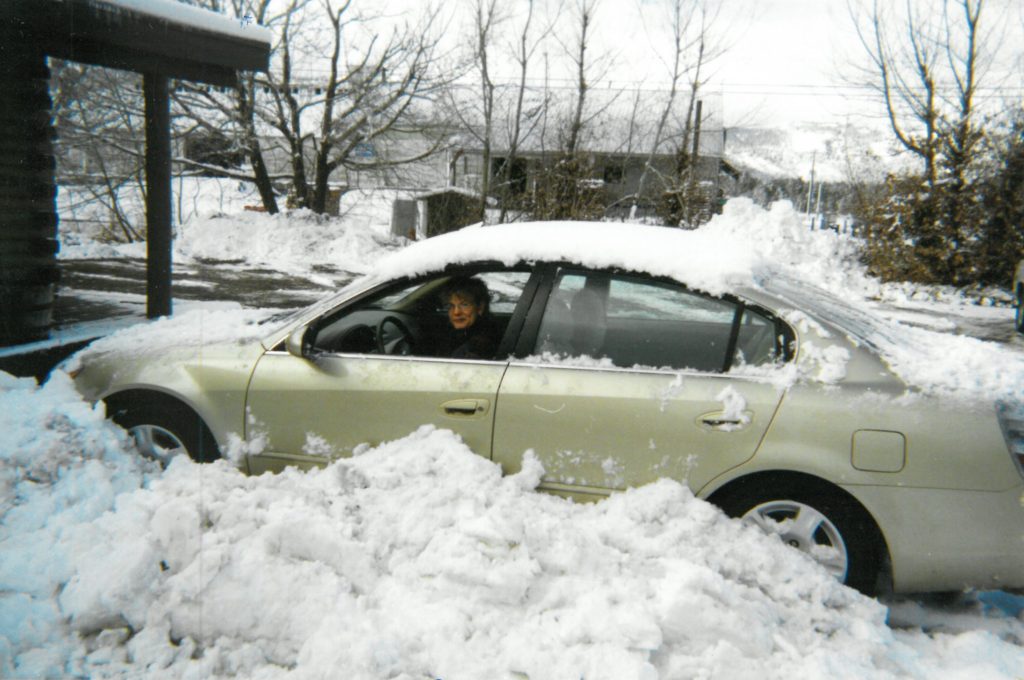 Kate in a car covered with piles of snow