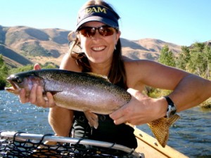 Jen Forbey holding a fish with water and mountains in the background