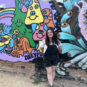 Chloe standing in front of a mural at Freak Alley gallery