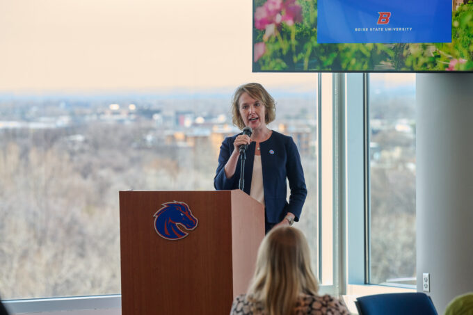 Leslie Durham speaks at a podium in a blue jacket