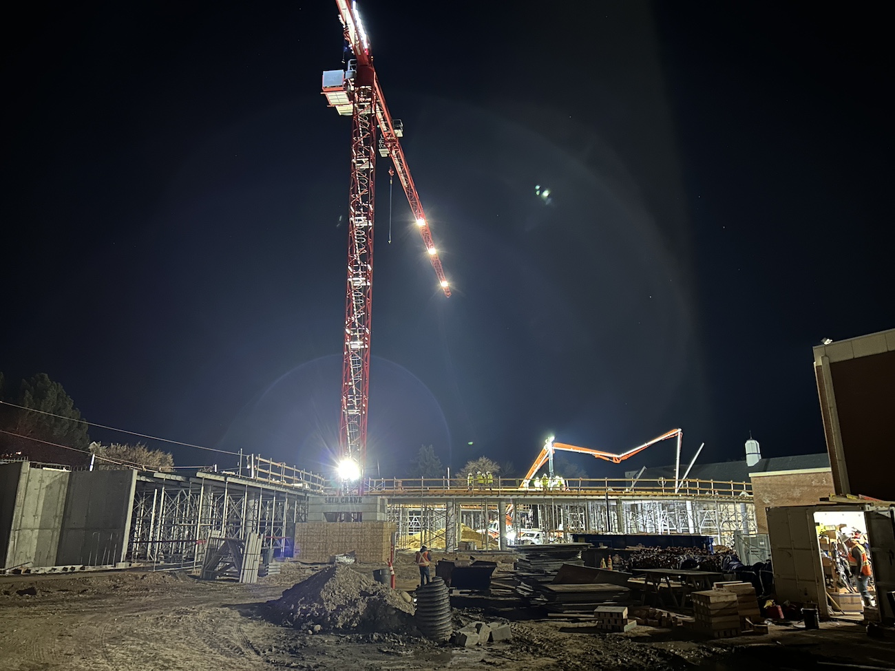 A construction site at night with an illuminated crane