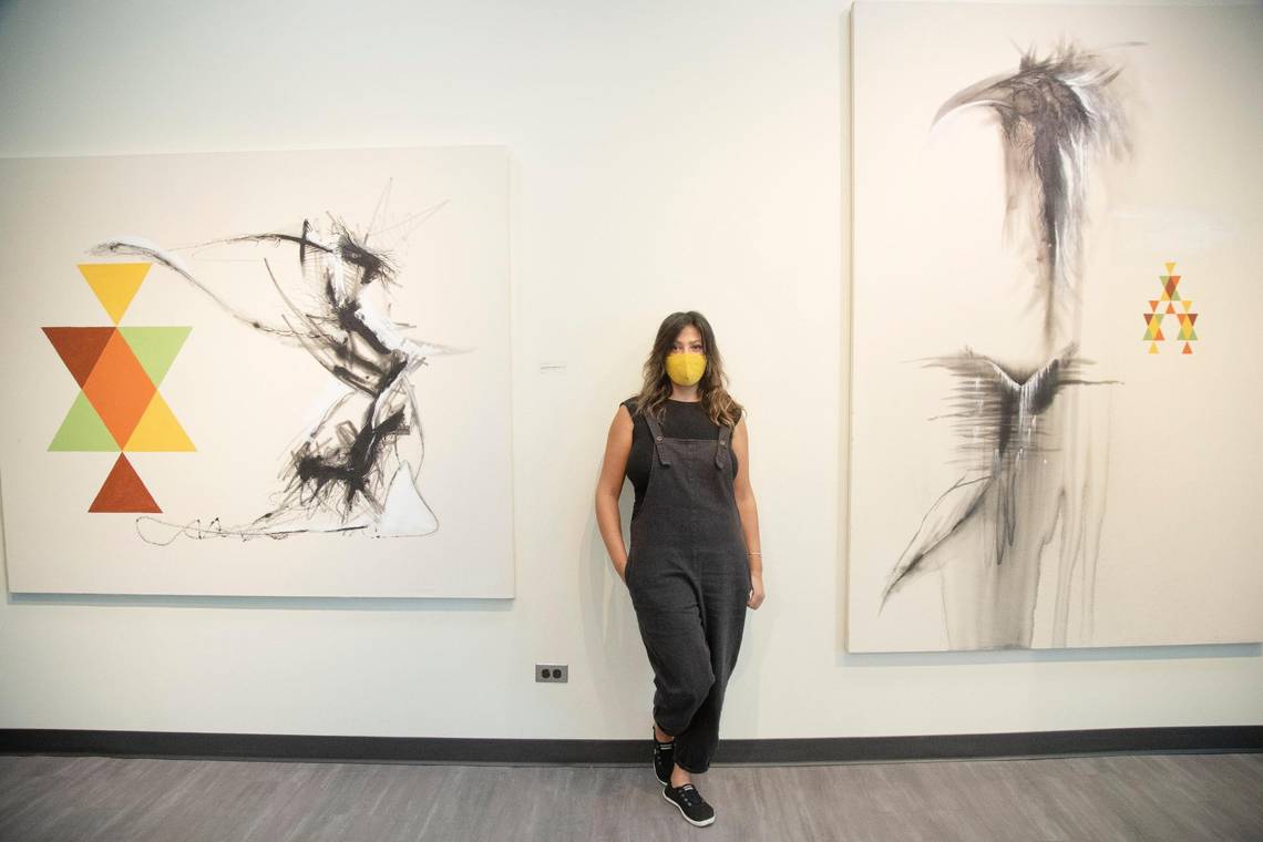 Jasmin stands in gallery between two of her art installations