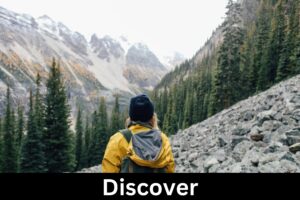 A person in the mountains looking into forest surrounded by mountains with the word Discover underneath.