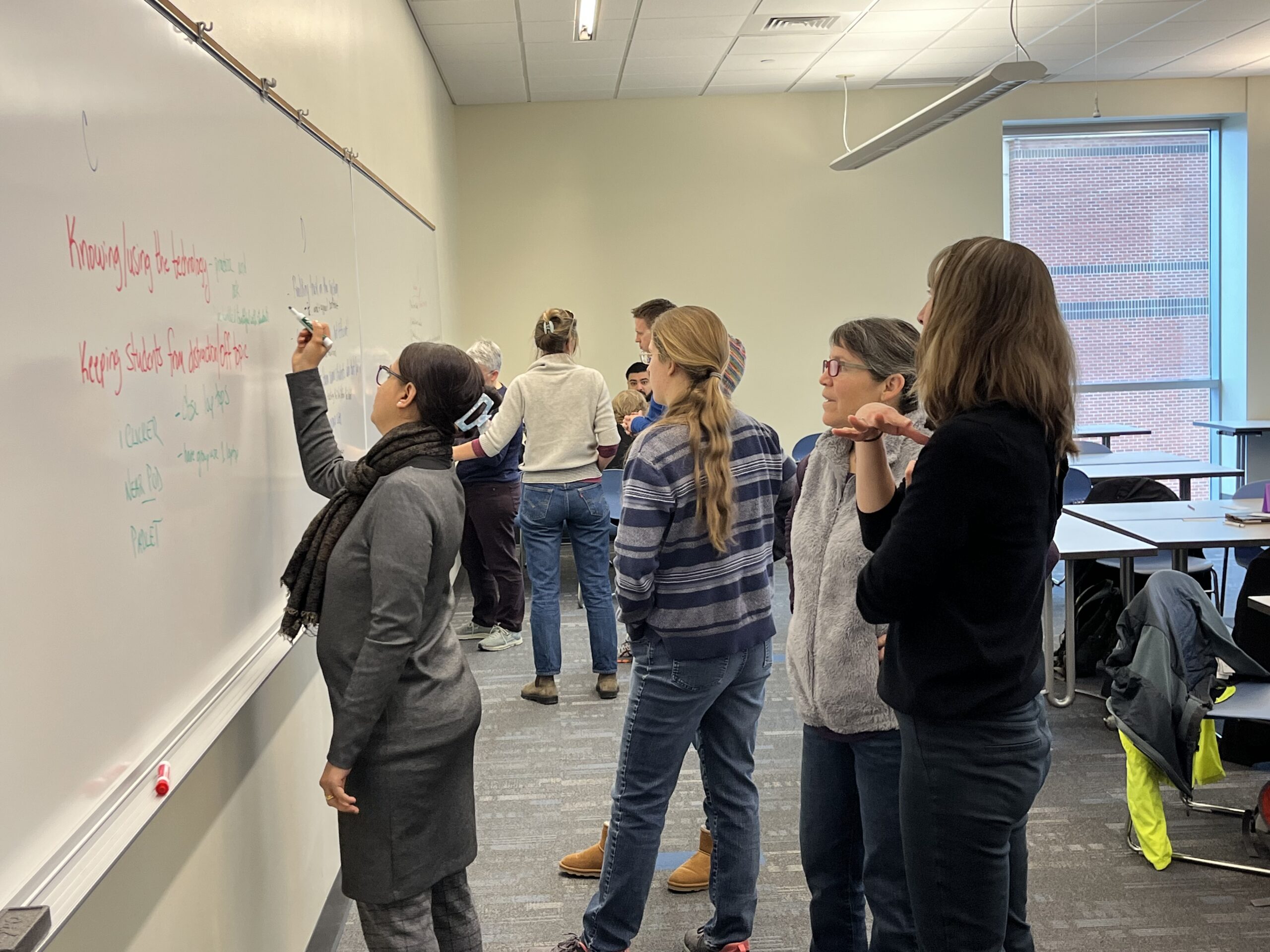 Faculty write on whiteboard during workshop