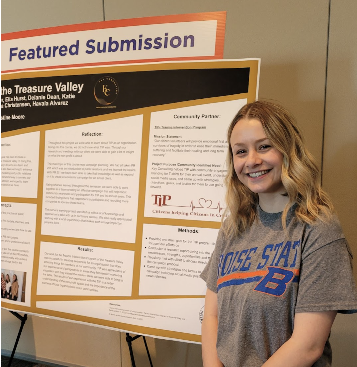 Student stands beside her service learning poster