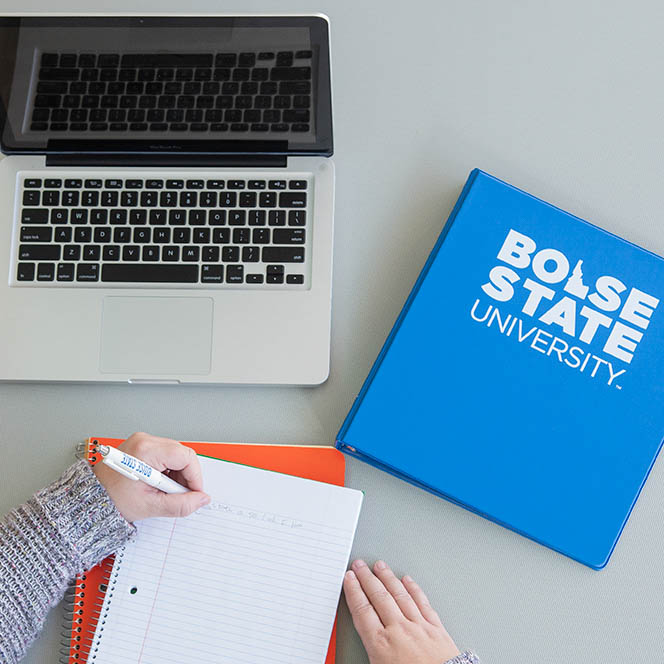 Student writes on Boise State brand notebook