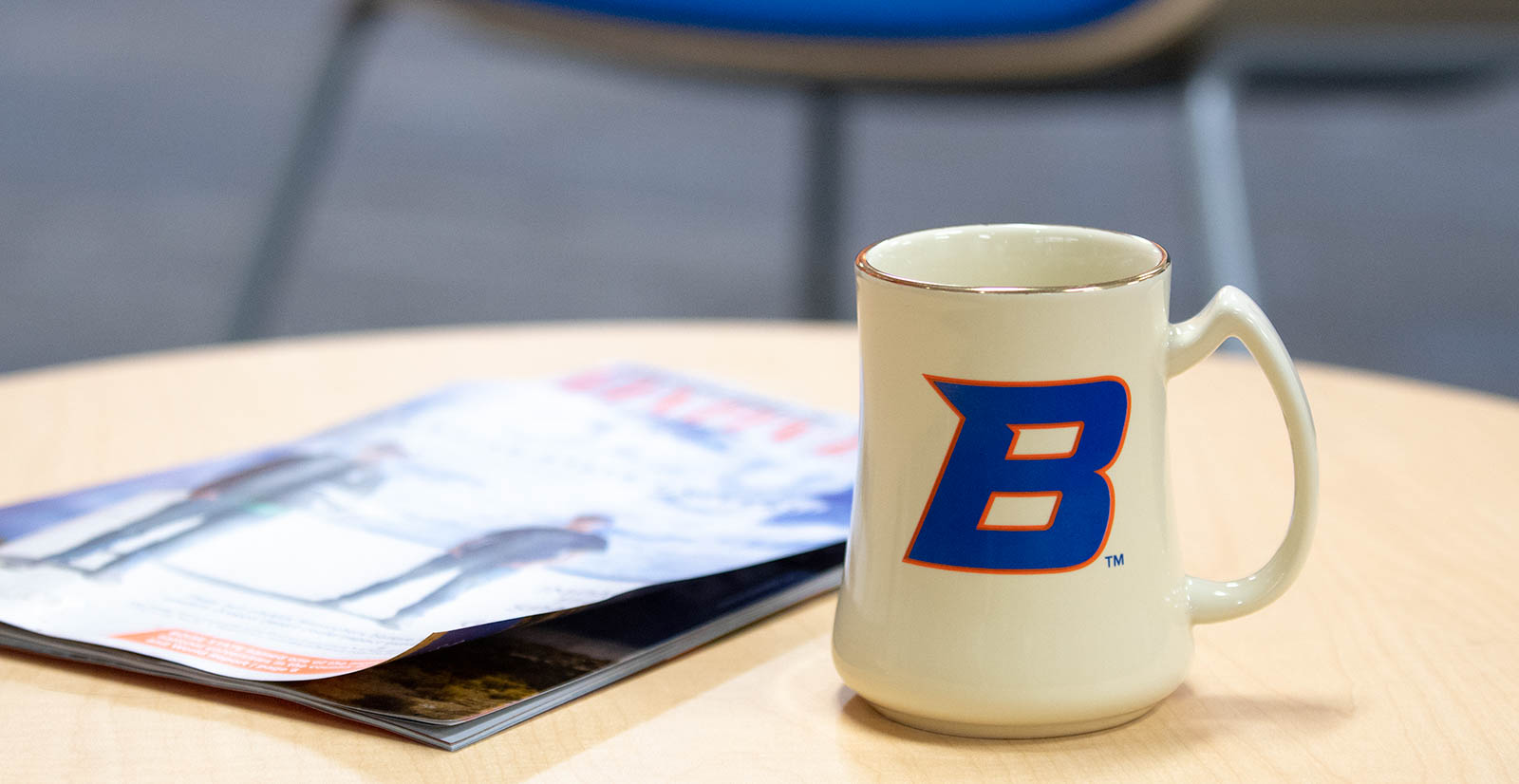 A Boise State themed coffee cup rests on a table