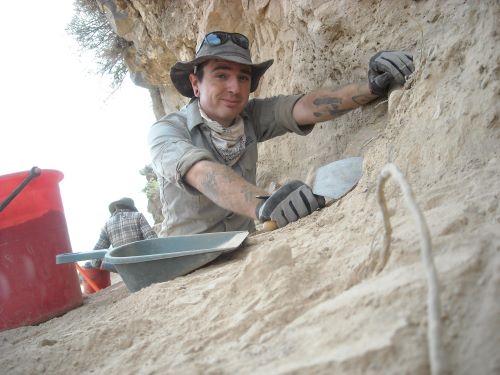 Jayson Gill climbing on rocks during a archeological dig