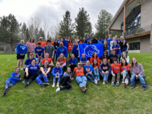 Group of about 50 students and staff in blue and orange outdoors