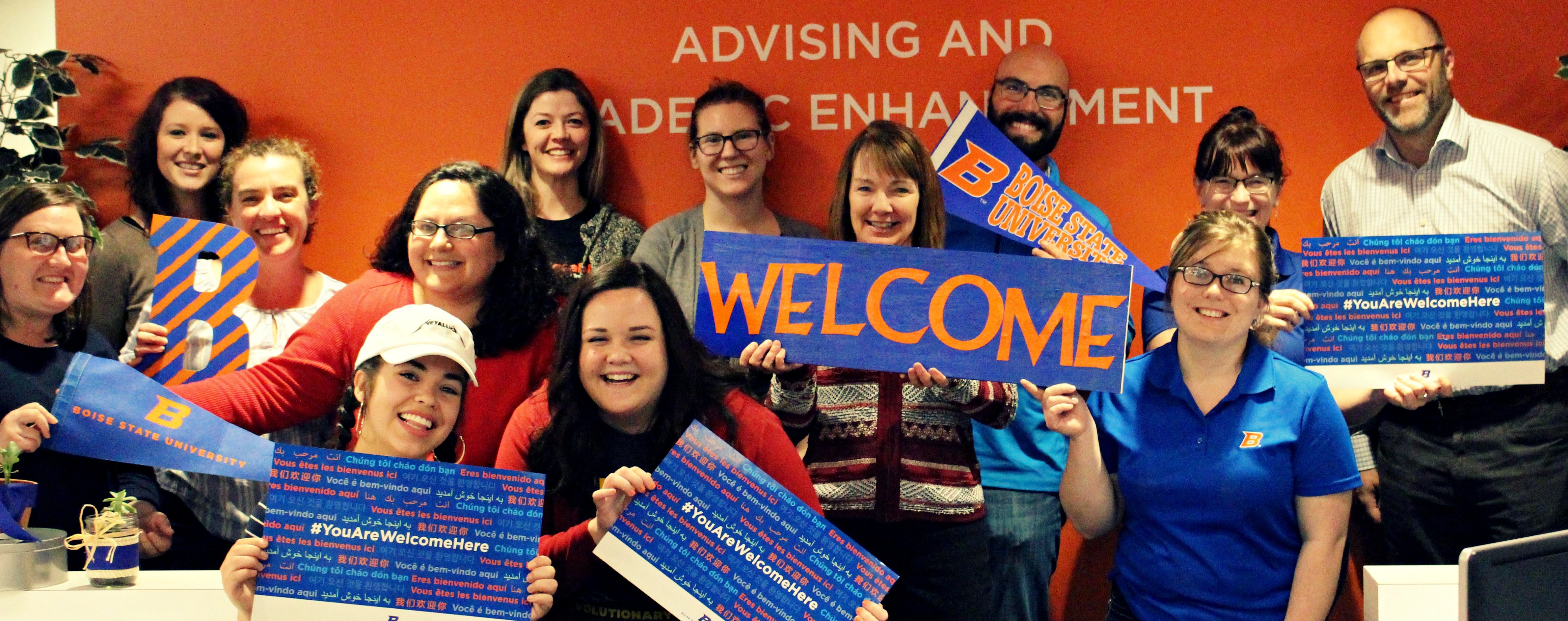 AASC staff pictured together and holding You Are Welcome Here signs.
