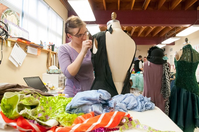 A seamstress works on a costume piece