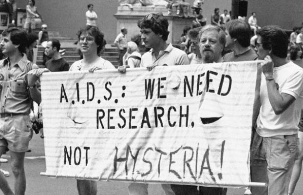 Marchers holding banner that says A.I.D.S: We Need Research Not Hysteria