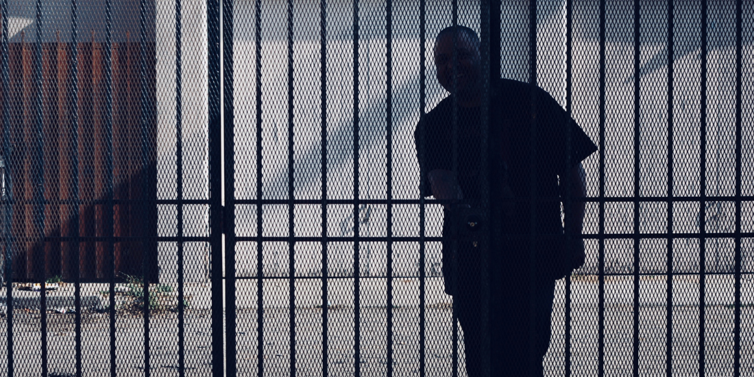 man silhouetted behind a fence in prison