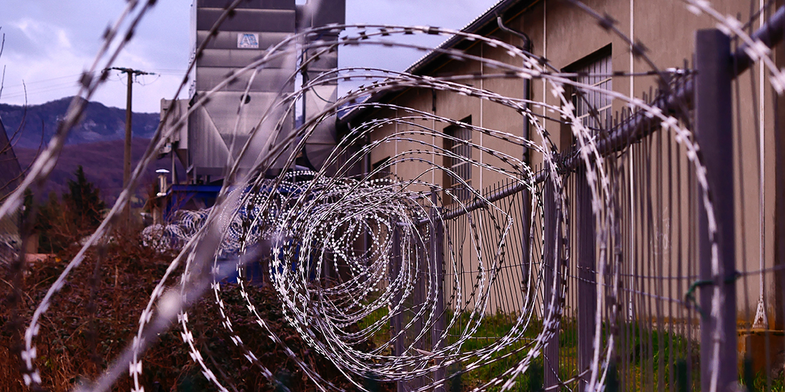 Razor wire runs along the fence of a prison