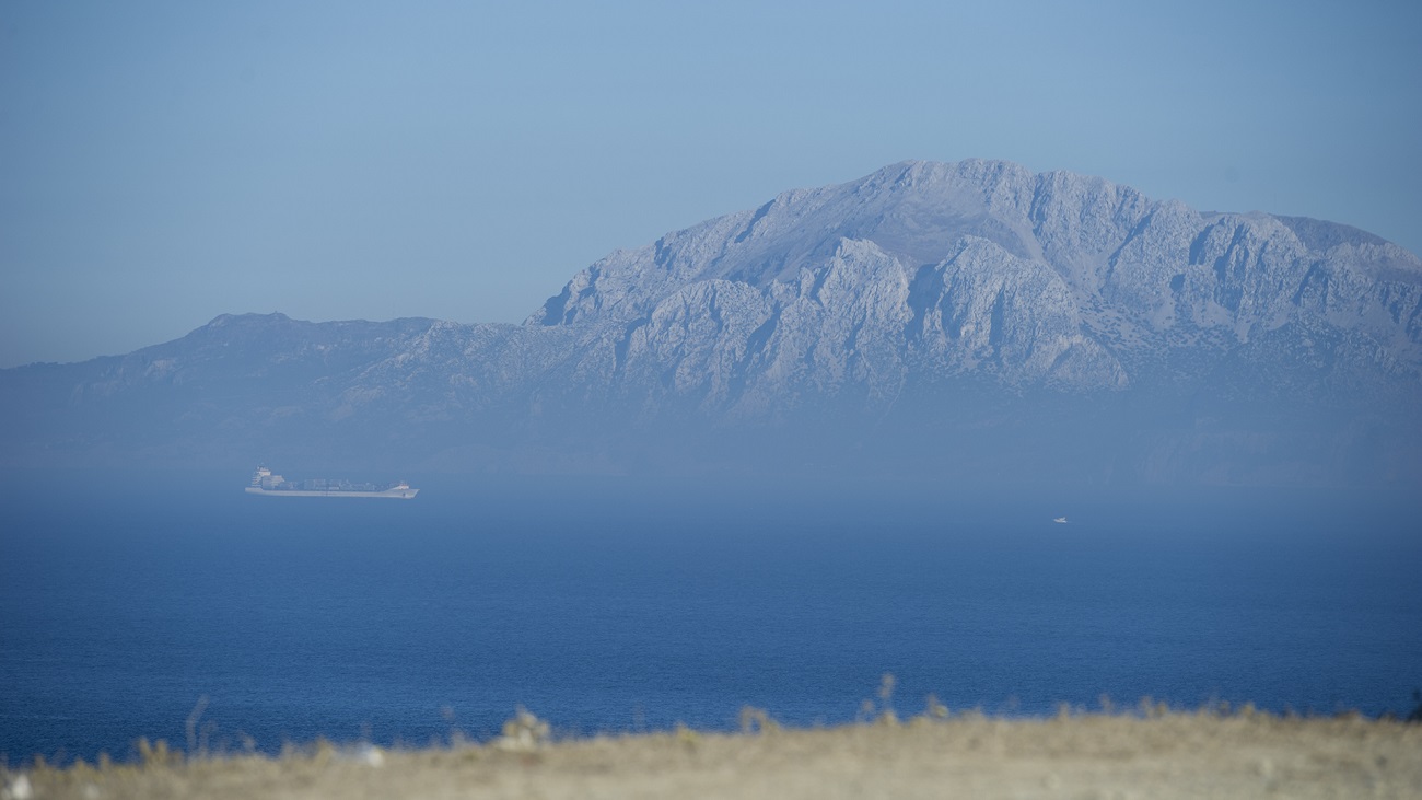 View across the Strait of Gibraltar from Tarifa, Spain, with a large ship at sea and the mountains of Jebel Musa in Morocco in the distance