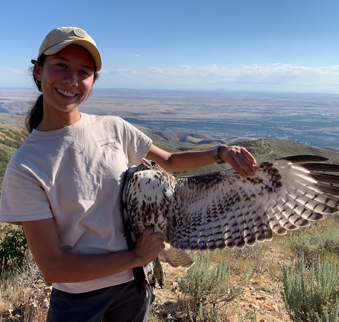 Raptor Biology student Nora Honkomp holding a hatch-year red-tailed hawk in Idaho foothills