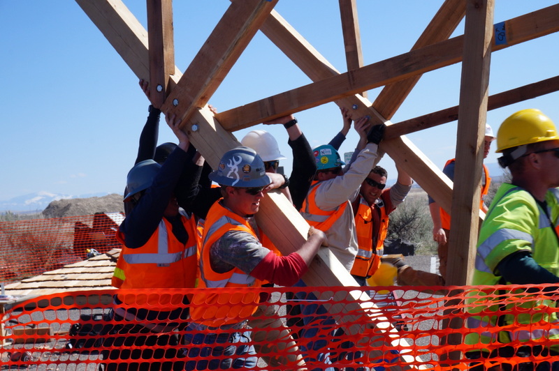 group of construction workers holding up a wood structure