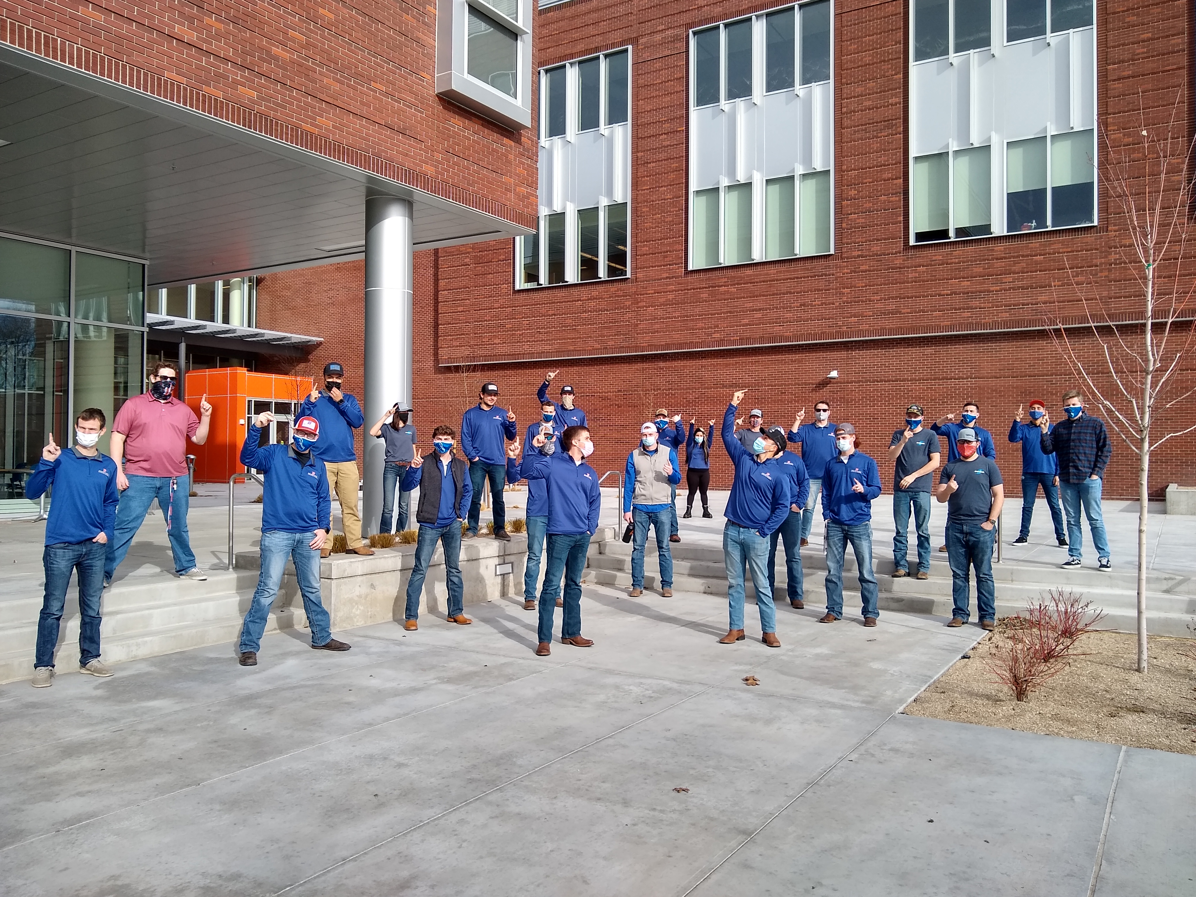 Construction Management students stand outside building, physically distanced and wearing masks