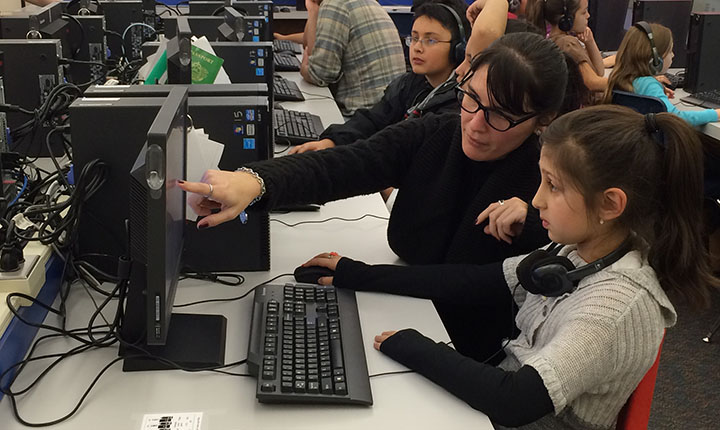 Teacher guiding young girl on a computer