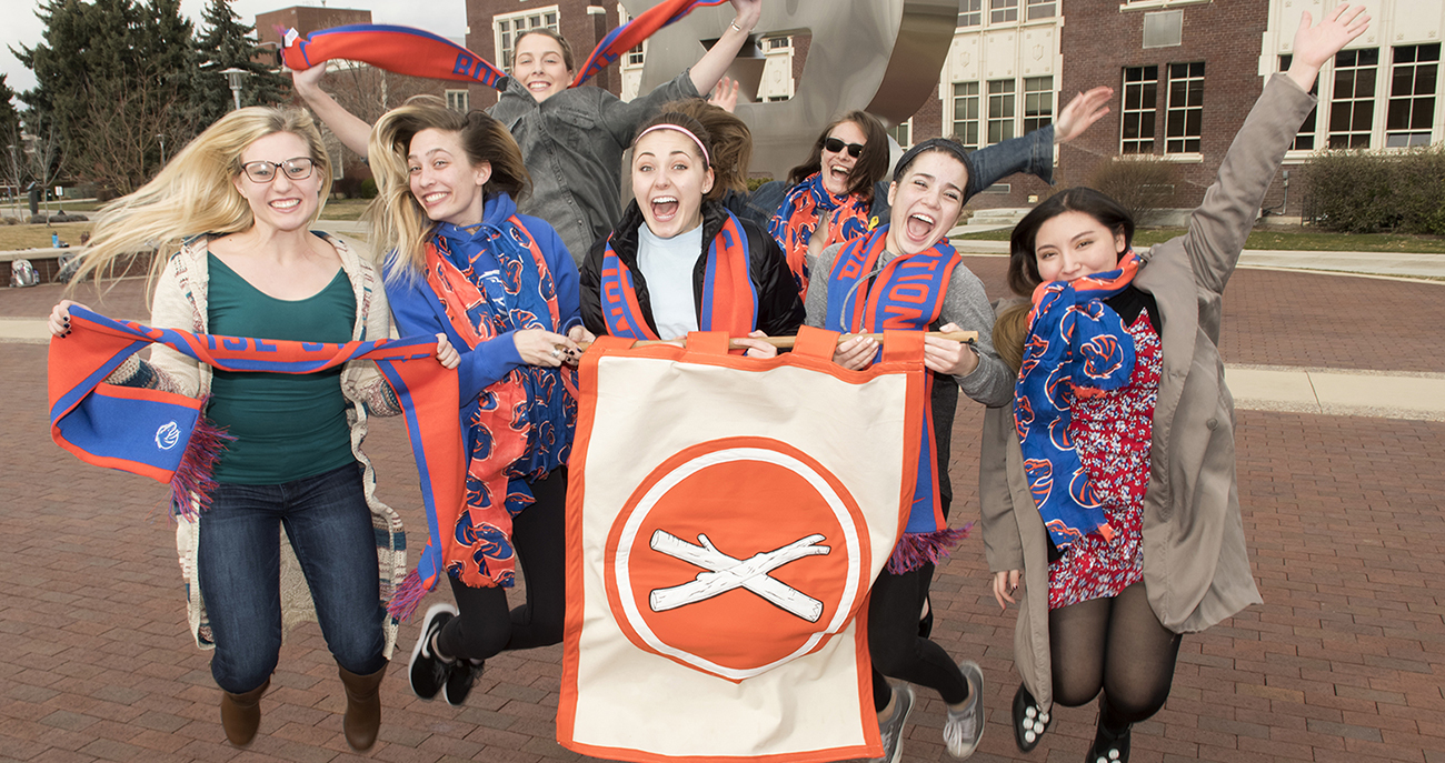 seven people holding a treefort flag and jumping