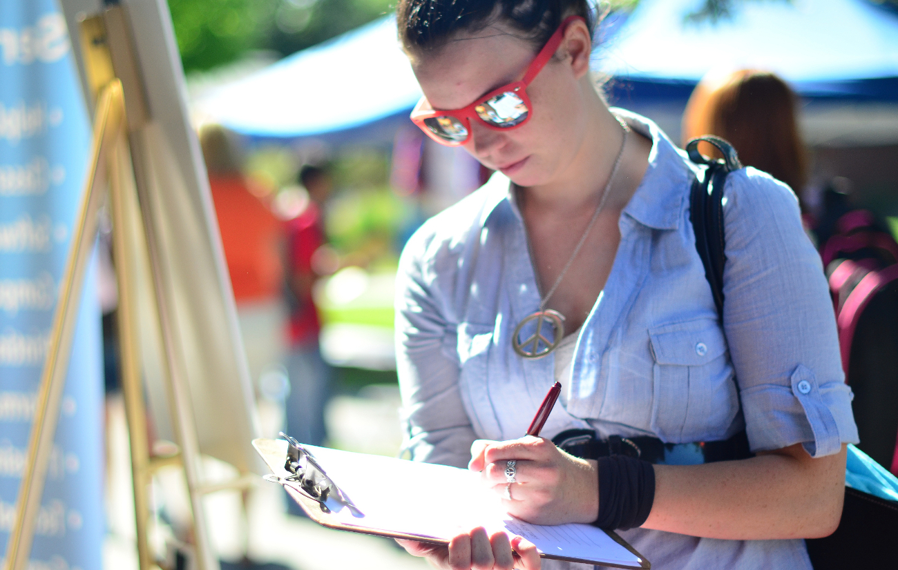 woman with sunglasses writing on a clipboard