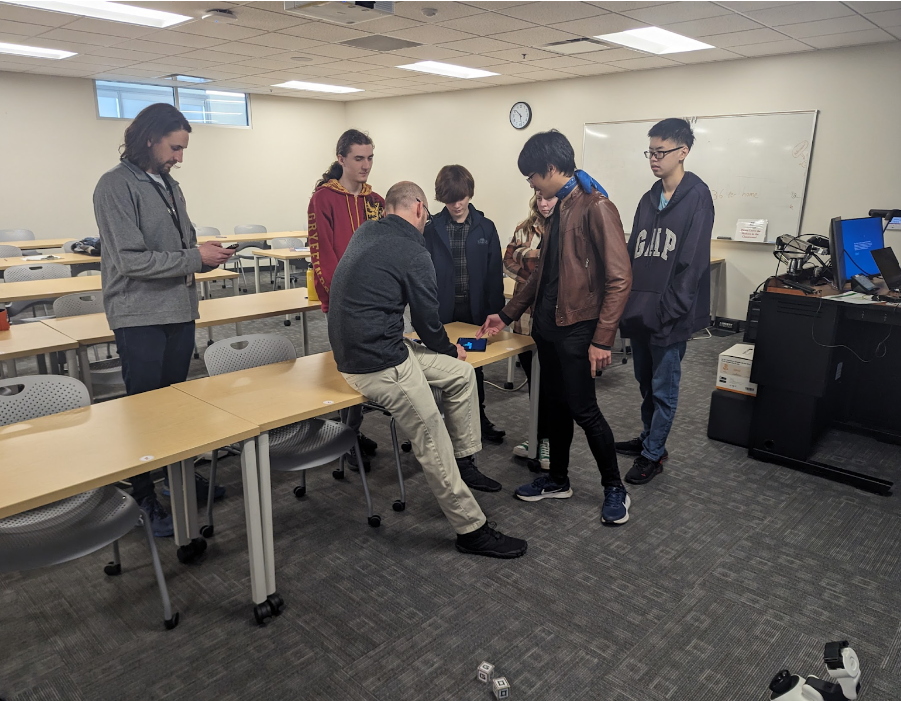 Image of a group of high school students learning about block programming on a Cosmo robot.