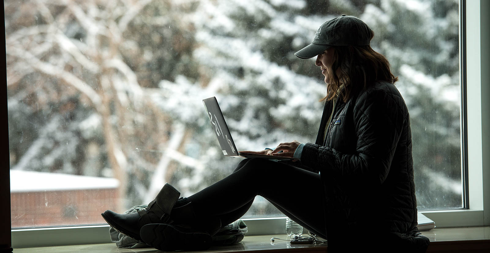 woman sitting in window sill with a laptop on her knees