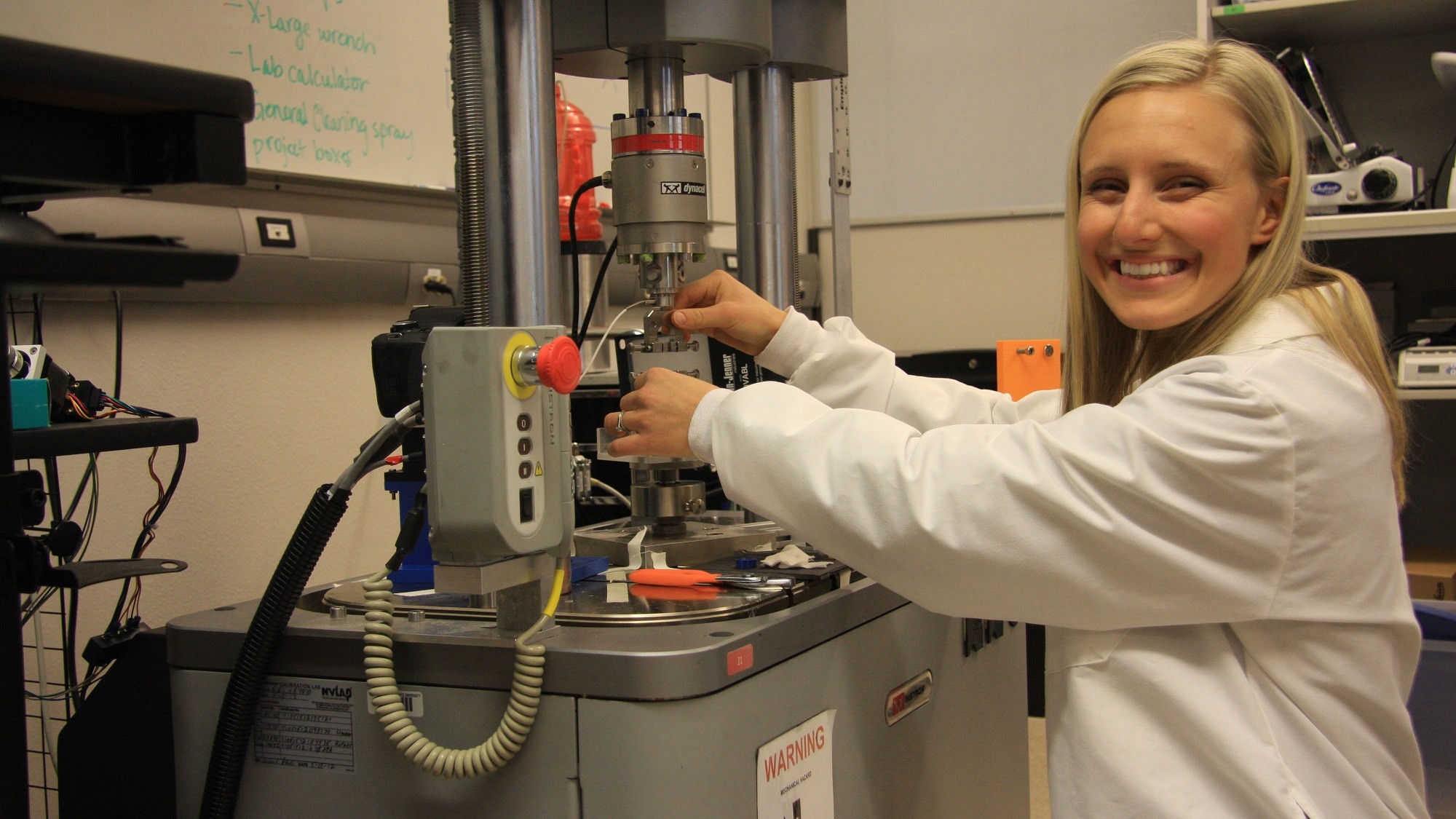 a woman in a lab coat putting a sample in testing equipment