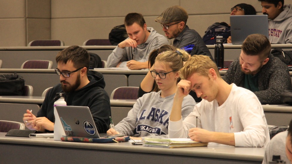 three students sitting in a lecture hall