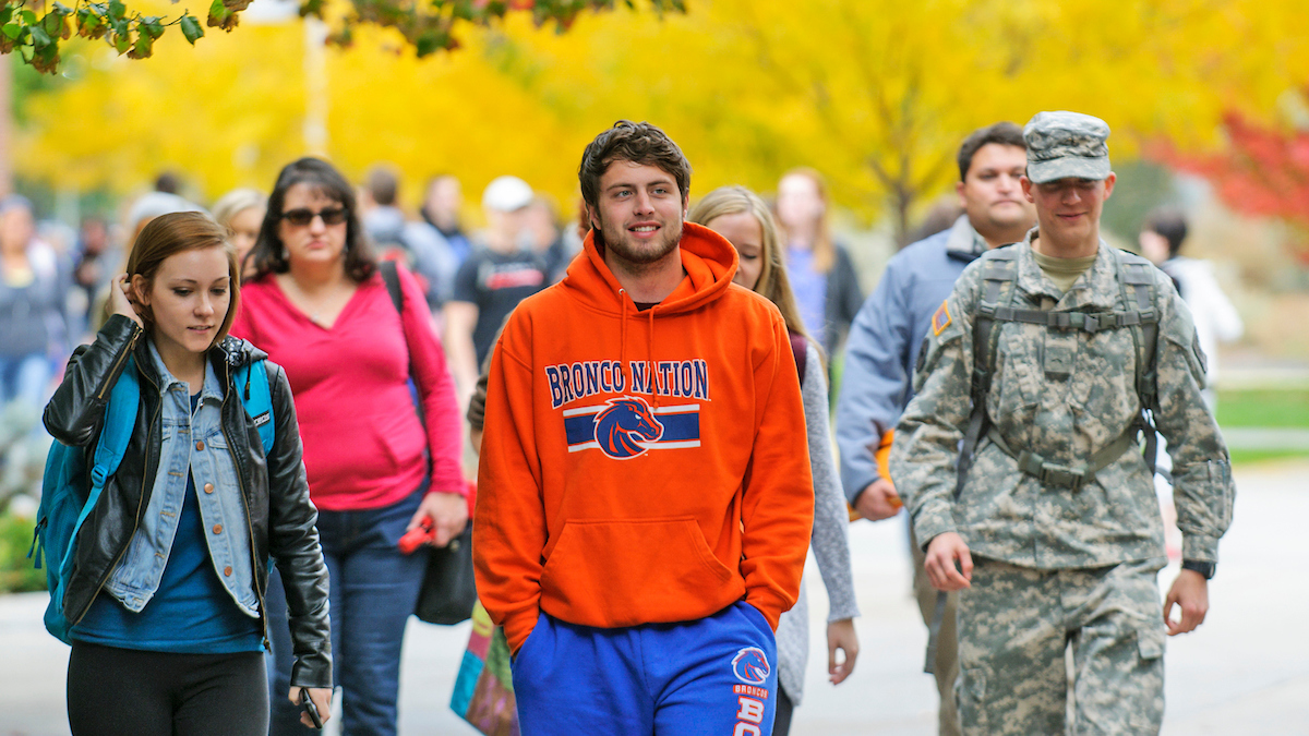 Students walking down a sidewalk in autumn