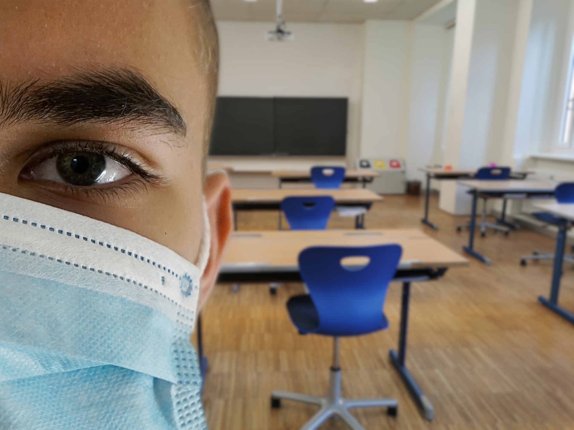 face of student wearing mask with empty classroom behind them