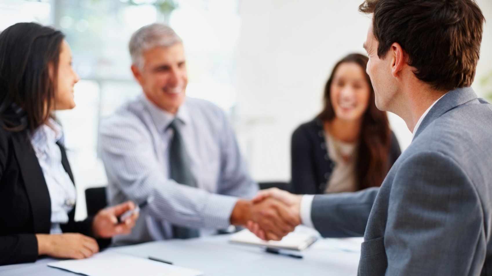 man offering handshake with panel of professionals