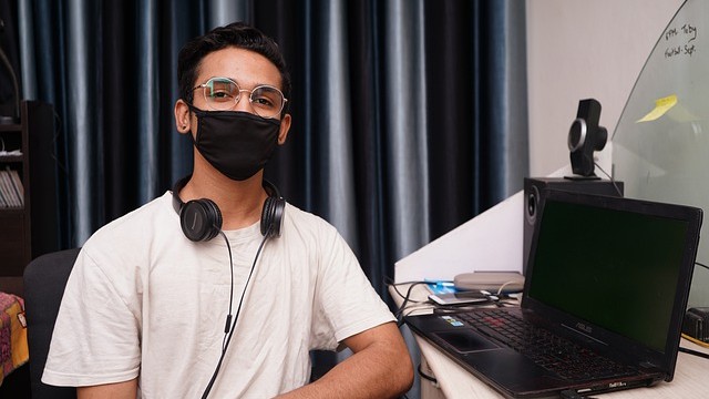 student with mask at laptop