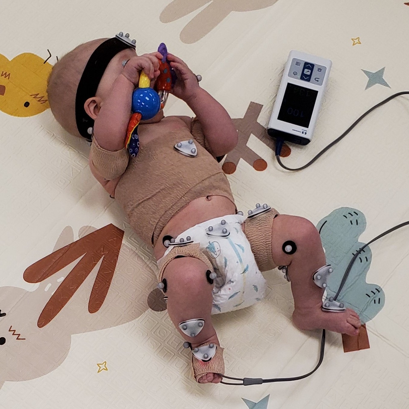 infant with sensors on play mat