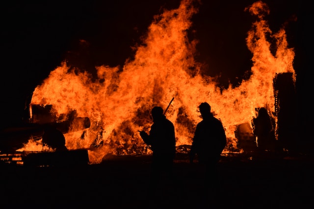 firefighters in front of a huge fire at night