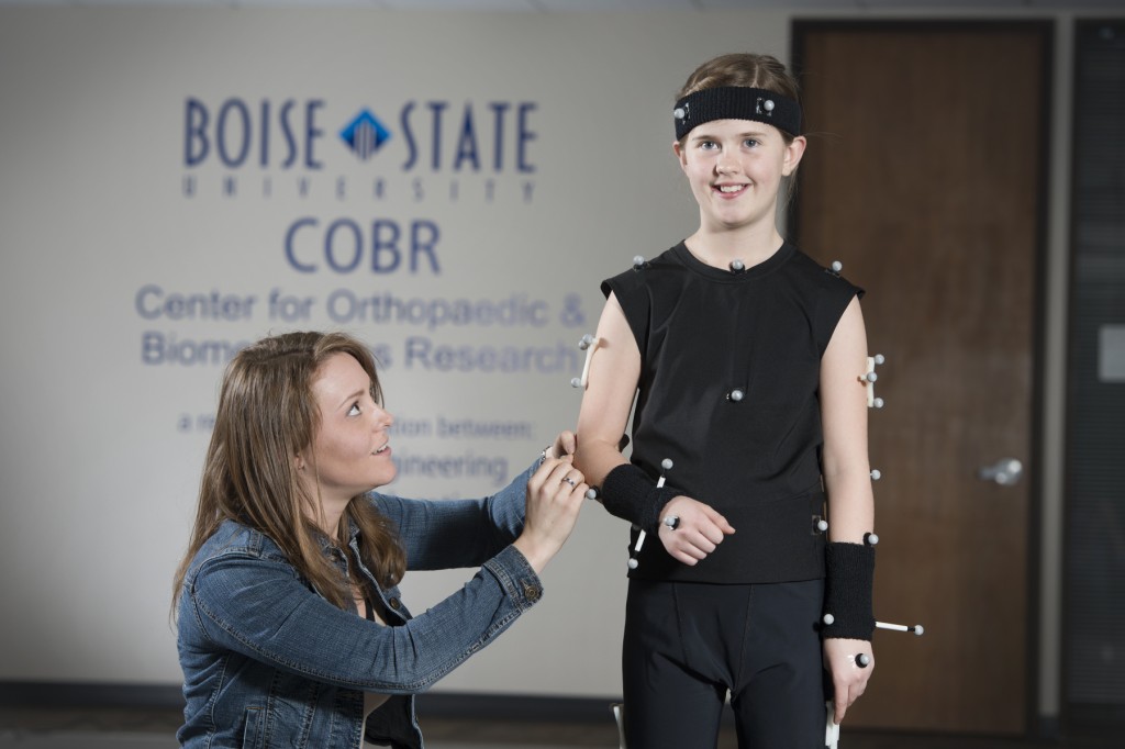 A woman fitting a child with motion capture sensor nodes
