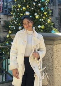 Chloe Yalung standing in front of a Christmas tree, dressed in winter white outfit