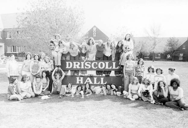 A large group of students gathered around a sign labeled "Driscoll Hall".