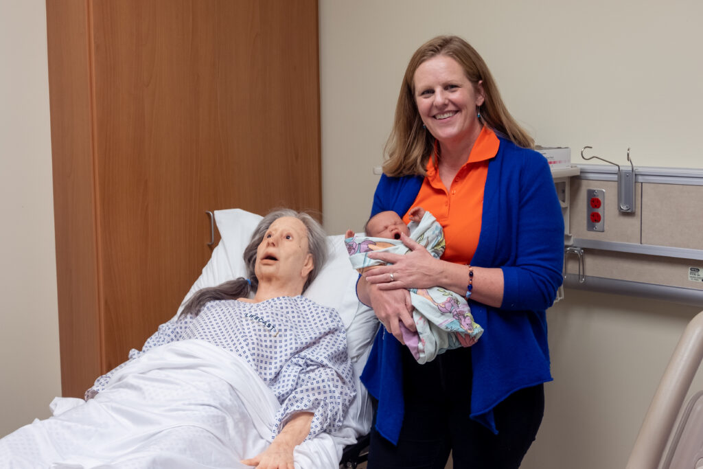Dr. Kelley Connor with two low fidelity manikins, a baby, and elderly woman.